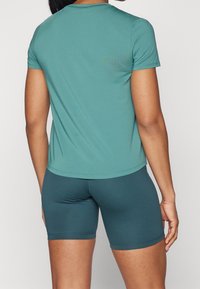 Teal tränings t-shirt med korta ärmar, slät textur och rund halsringning, i kombination med matchande åtsittande shorts, båda med sömlöst design.