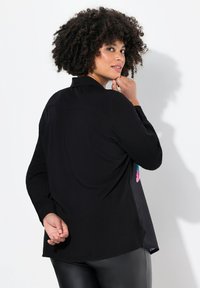 Zwarte langekousen shirt met een kraag, voorzien van kleurrijke accenten aan de zijkanten, een gladde textuur en een ontspannen pasvorm. Op maat gemaakte achterkant.