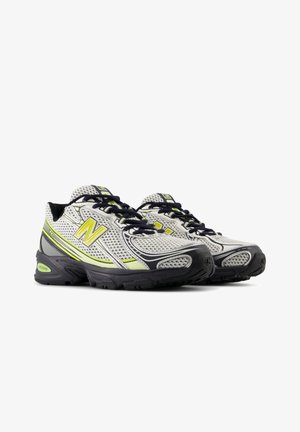 Zapatillas deportivas con parte superior de malla gris, acentos en amarillo neón, cordones azul oscuro y suelas de goma negra con textura para un mejor agarre.