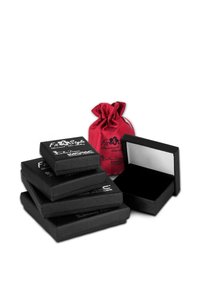 Des boîtes à bijoux noires texturées empilées de différentes tailles, accompagnées d'un sac à cordon en satin rouge assorti. Certaines boîtes s'ouvrent pour révéler des intérieurs noirs.