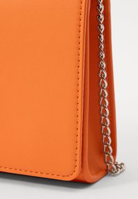 Orange faux leather bag with a smooth texture, featuring a silver chain strap, rectangular shape, and visible stitching details.