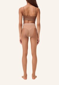 Collant nude con design a vita alta, caratterizzati da una texture trasparente, dettagli contornati e una cintura liscia. La vista posteriore mostra una copertura elegante delle gambe.