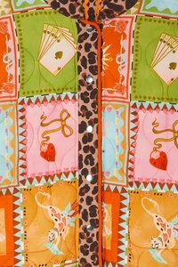 Gequiltede jas met kleurrijk patchwork van speelkaarten, harten en dierenprints; hoogtepunten zijn de met luipaardpatroon versierde rand en drukknopen.