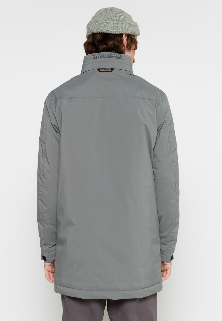 Giacca impermeabile grigia con un colletto alto, leggermente allungata sul retro e una texture pulita e liscia. Presenta un dettaglio del logo sul colletto.