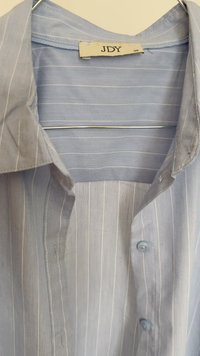 Camisa de botão azul-claro com riscas verticais brancas, um colarinho clássico e botões azuis, feita de um tecido leve com uma textura suave.