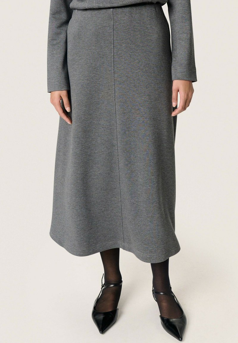 Gonna midi grigia realizzata in un materiale morbido con una leggera lucentezza. Presenta una forma dritta, una texture liscia e un orlo semplice. Indossata con scarpe nere a punta.