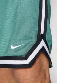 Roheline võrkmaterjalist korvpallishorts, musta ja valge �äärisega, mille alumises vasakus servas on valge Nike logo.