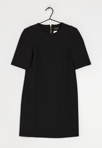 Svart klänning med kort ärm och rund halsringning, samt en dold dragkedja i ryggen. Tillverkad av slät tyg och har en skräddarsydd passform.