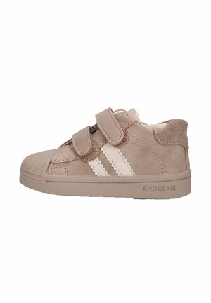 Lichtbruine peutersneaker met twee witte strepen, dubbele klittenbandsluitingen, rubberen neuskap en "SHOESME" in de zool geperst.