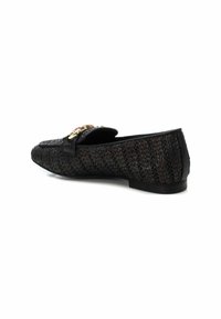 Mocasines negros de tejido con una correa de cuero y detalles de hardware en tono dorado. Tacón bajo y punta redonda con material superior texturizado.