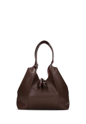 Hnědá kožená kabelka s kulatými rukojeťmi a dekorativními uzly na přední straně, stojící vzpřímeně na bílém pozadí.