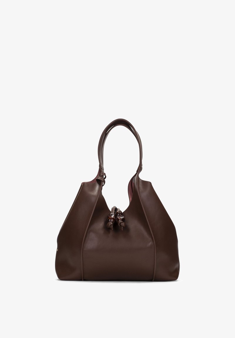 Sac à main en cuir marron avec poignées arrondies et nœuds décoratifs à l'avant, debout contre un fond blanc.