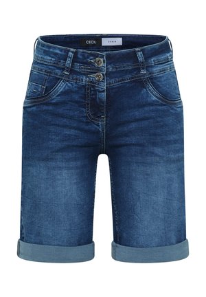Frau trägt eine blaue Kappe, gestreiftes kurzärmeliges Shirt, aufgerollte Jeansshorts, beige Sneakers und hält eine große dunkelblaue Tragetasche.