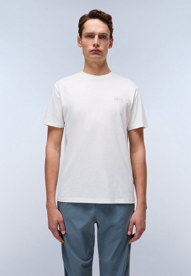 Tricou alb din bumbac, cu un design cu mânecă scurtă și un logo subtil în bej deschis pe partea stângă a pieptului. Textură netedă, decolteu rotund.