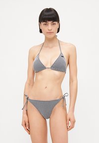 Svart og hvit rutete bikini med trekantet topp med halterneck-bindinger og matchende sideknute-bunn, laget av stretchstoff.