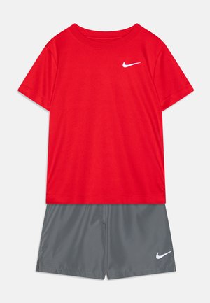Sarkans īsām piedurknēm T-krekls ar baltu Nike logotipu uz krūšu daļas, apvienots ar pelēkiem šortiem, kas rotāti ar mazu baltu Nike logotipu. Abi izgatavoti no viegla materiāla.
