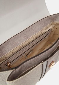 Beige and white handbag with textured exterior, gold-tone hardware, and patterned interior featuring multiple compartments and a zipper pocket.