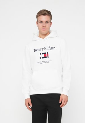 Un sweat à capuche blanc en coton, avec un grand logo aux accents rouge, bleu et noir. Comprend une poche avant et un cordon de serrage au niveau de la capuche.