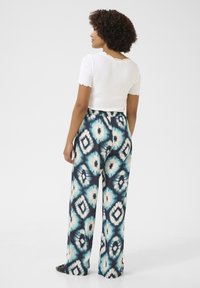 Valge ribaga top lühikeste varrukatega, koos laia jalaga pükstega, millel on sinise ja kreemja diamondsidšiga tikkimiseks mõeldud mustri. 