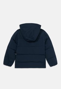 Marineblå pufferjakke med hette, med horisontalt quiltet design, elastiske mansjetter og en myk tekstur. Bakfra viste.