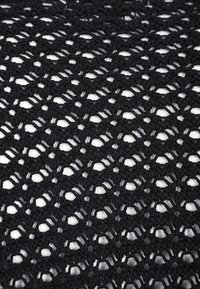 Tessuto all'uncinetto nero con un motivo a diamante e sezioni a rete aperta. Superficie texturizzata con punti uniformi e filato lucido.