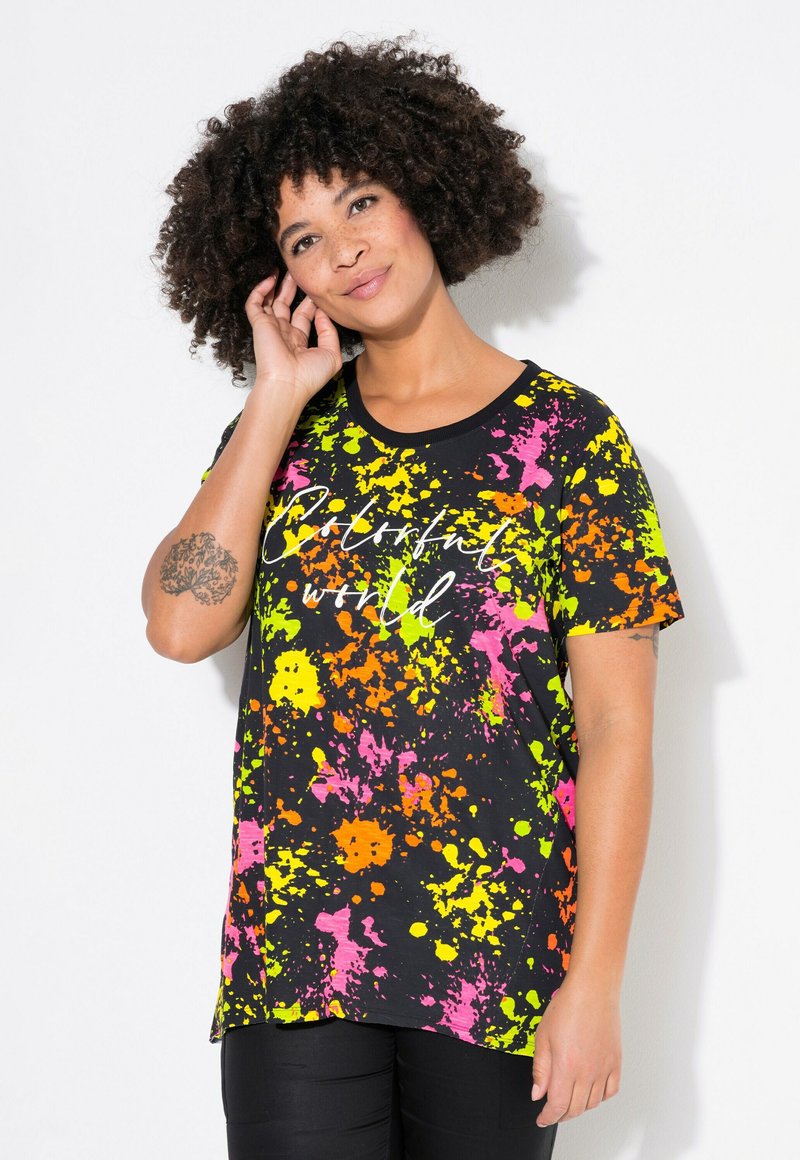 Camiseta negra con un vibrante patrón salpicado en rosa, naranja y verde, que presenta el texto "Mundo Colorido" en una fuente cursiva. Manga corta.
