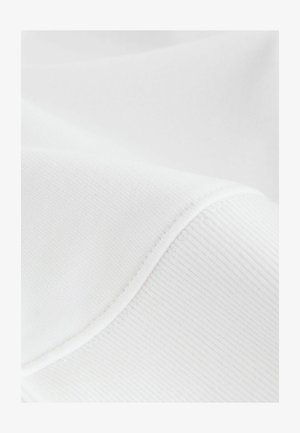 Hvidt stof med en glat og ribbet tekstur, der har subtile syninger og kurver, hvilket illustrerer et blødt, let tekstil.