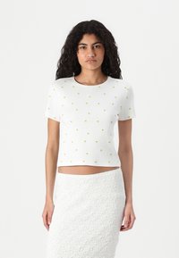 Witte cropped t-shirt met korte mouwen, voorzien van gele bladerenpatronen. Zachte, ribbelstructuur aanvult een aansluitend ontwerp.