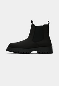 Svarte ankelstøvler med elastiske sidestykker, teksturert gummisåle, rund tå og løkker for enkel påkledning. Glatt syntetisk materiale.