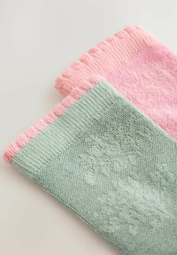 Två stickade strumpor: en mintgrön med ett texturerat mönster, och en ljusrosa med en vågig kant, båda mjuka och uttänjbara.