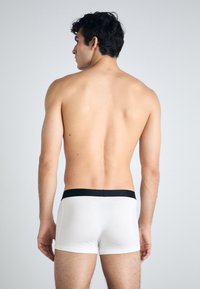 Weiße Boxershorts aus weichem Stoff mit einem schwarzen elastischen Bund, im engen Schnitt und mit glatter Textur.