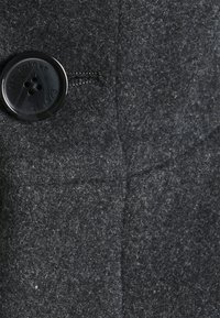 Abrigo de lana gris oscuro con un tejido texturizado, diseño clásico y un gran botón negro con cuatro agujeros cosidos.