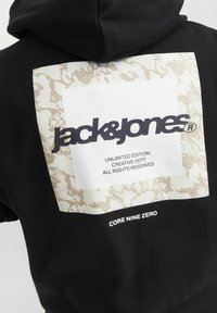 Czarna bluza z kapturem z dużą prostokątną grafiką z beżowym abstrakcyjnym wzorem oraz czarnym napisem "jack&jones" i "CORE NINE ZERO."