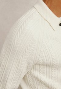 Gestrickter Pullover in Off-White, mit einem gerippten Kragen, strukturierten Mustern und einem glatten Stofffinish.
