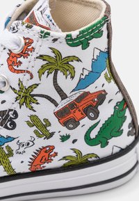 Wysokie trampki z białego płótna z kolorowymi ilustracjami dinozaurów, palm, gór, kaktusów oraz pomarańczowego pojazdu. Czarna podeszwa.