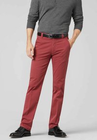 Rode chino's voor heren met een gladde afwerking, rechte pijpen en zijzakken. Draagt een grijs langemouwen shirt en een zwarte riem.