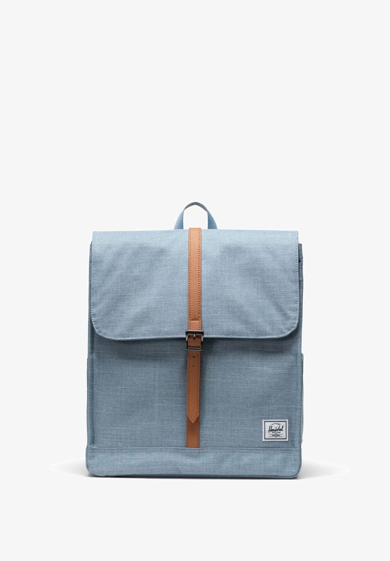 Plava platnena ruksak s preklopom, smešani kožni remen i metalnom kopčom. Ima malu oznaku loga sprijeda.
