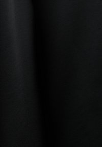 Gros plan sur un tissu noir lisse avec une texture tissée subtile et des plis doux créant des ombres délicates.