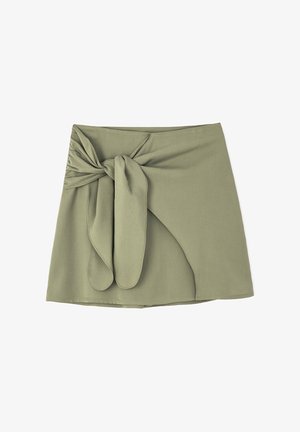 Olivově zelená mini sukně z měkké tkaniny, se zapínáním na uzel vpředu a mírně asymetrickým spodním lemem, s hladkou strukturou.