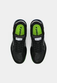 Des chaussures de sport noires disposent d'un dessus en synthétique, de semelles intérieures vertes et d'accents bleus. Le design comprend une surface texturée et un lacet standard.