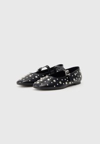 Black leather flats with a pointed toe, adorned with silver studs and a strap with a metal buckle. Flat sole, simple design.