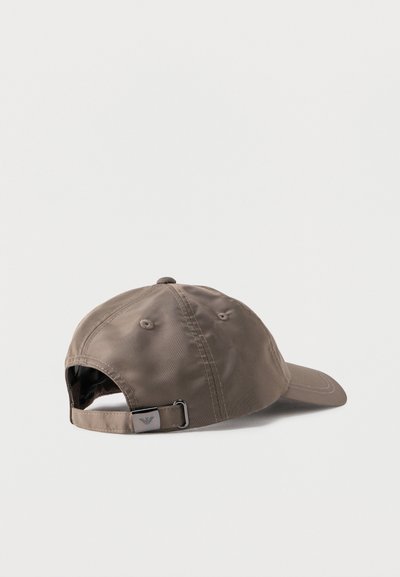 Καφέ ρυθμιζόμενο καπέλο μπέιζμπολ με μεταλλικό κούμπωμα και μικρό λογότυπο στο λουράκι, εμφανιζόμενο από πίσω σε λευκό φόντο.