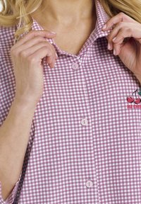 Fioletowo-biała koszula w kratę z kołnierzykiem, z różowymi guzikami i luźnym krojem, wykonana z teksturowanej tkaniny.