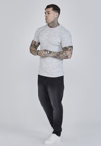 Korte mouw, lichtgrijze gestreepte t-shirt gecombineerd met donkere jeans en witte sneakers, met een aansluitend ontwerp en gestructureerde stof.