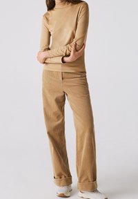 Tan mock turtleneck top paired with light brown corduroy wide-leg pants. The pants have a textured ribbed pattern and rolled cuffs.
