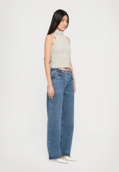 Maglione a collo alto a righe grigie e bianche, abbinato a jeans wide-leg azzurri a vita alta, con la classica stile a cinque tasche e orli curvi.
