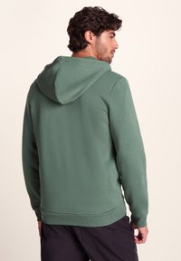 Green hoodie with a drawstring hood, ribbed cuffs, and hem. Smooth texture, casual fit, showcasing a plain design without patterns.