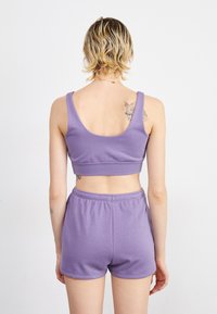 Purple cotton athletic crop top and matching shorts with a fitted design. The fabric has a smooth texture, featuring a band at the waist.