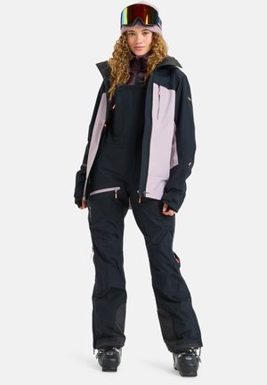 Casaco de esqui e calças de neve em preto e roxo claro; as características incluem fechos éclair, bolsos e um acabamento texturizado; acessórios com óculos coloridos.
