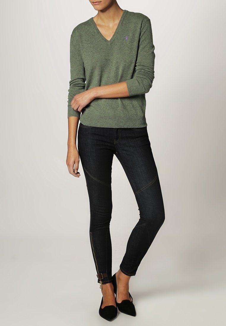 Zelený svetr s véčkovým výstřihem a žebrovanými manžetami, nošený s tmavými skinny džínami s prošíváním a zipy na kotnících; doplněný černými balerínami.